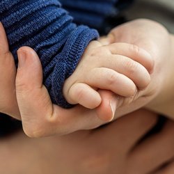 Erwachsene Hand hält die eines Babys
