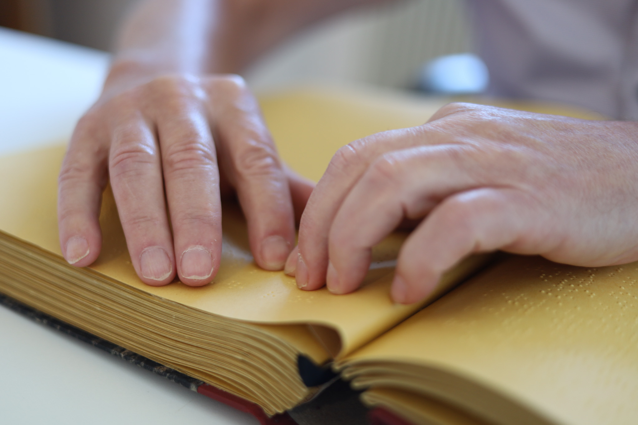 Hände beim Lesen eines Textes in Braille