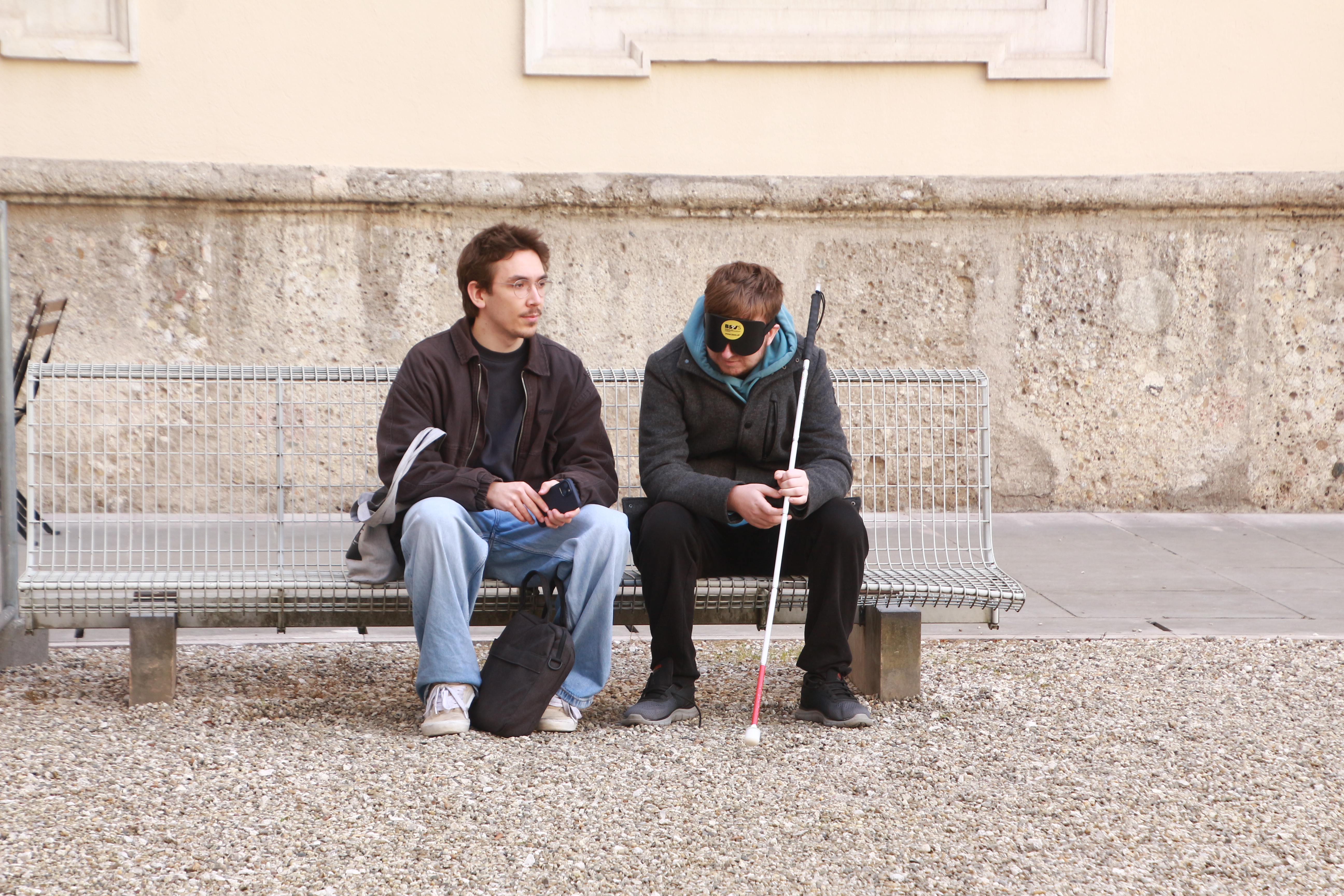 Studierende unterhalten sich auf einer Bank in der Salzburger Altstadt, einer mit Dunkelbrille und weißem Stock. | © Ute Brandhuber-Schmelzinger